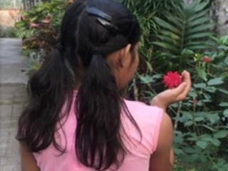 girl facing away from camera holding a flower