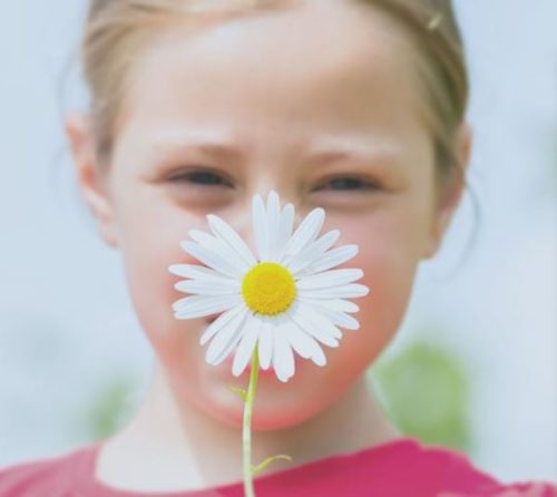 girl holding flower in front of her face