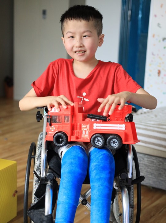 Boy in a wheelchair holding a fire engine