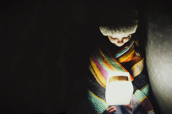 Girl wrapped in a blanket holds a solar light