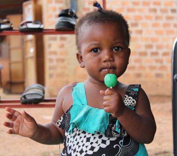 Uganda girl in green with a lollipop