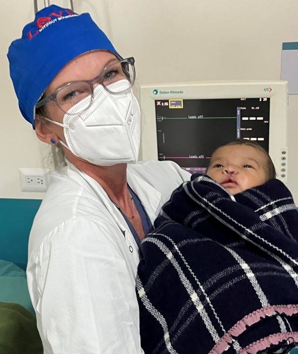Nurse holds baby following cleft lip repair surgery