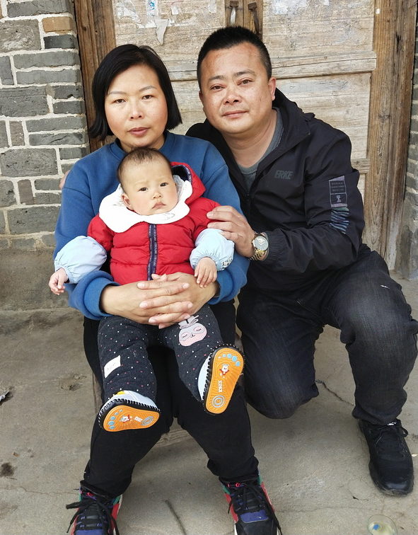 Parents holding baby girl in red coat in China