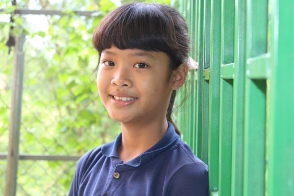 Cambodian girl in front of a green wall
