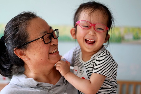 young girl wearing glasses being held by caregiver at China healing home