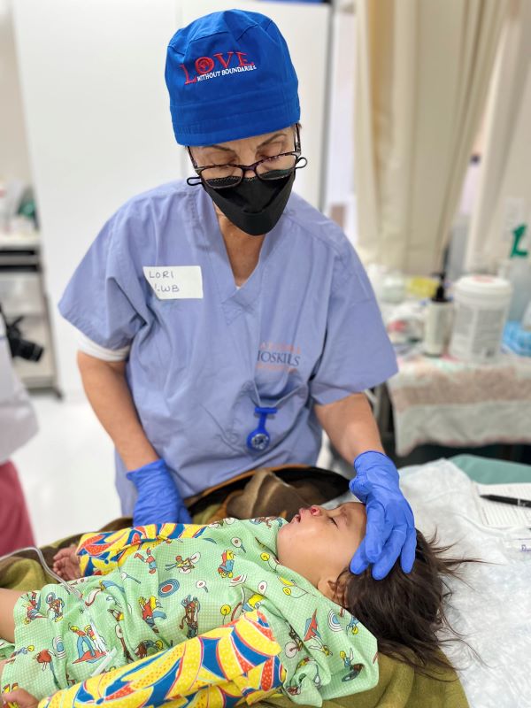 Nurse comforts girl after cleft repair surgery in Guatemala