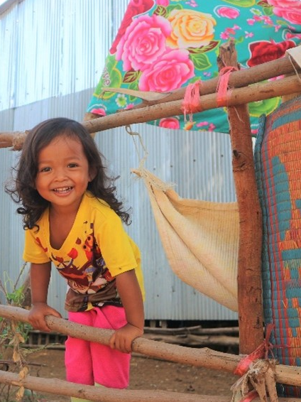 Smiling Cambodian girl standing in front of colorful fabrics