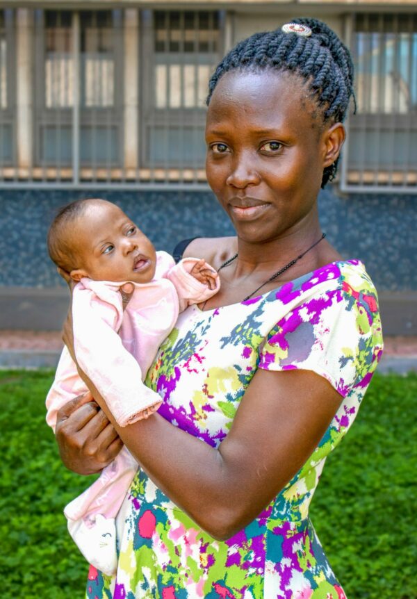 Uganda mom holding small baby in pink