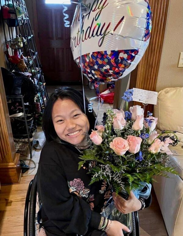 Teenage girl in a wheelchair holding balloons and roses