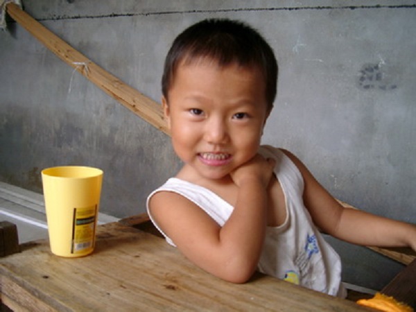 Girl in Chinese foster care next to a yellow cup