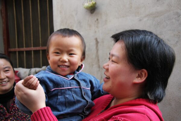 Chinese toddler being held by her foster mother