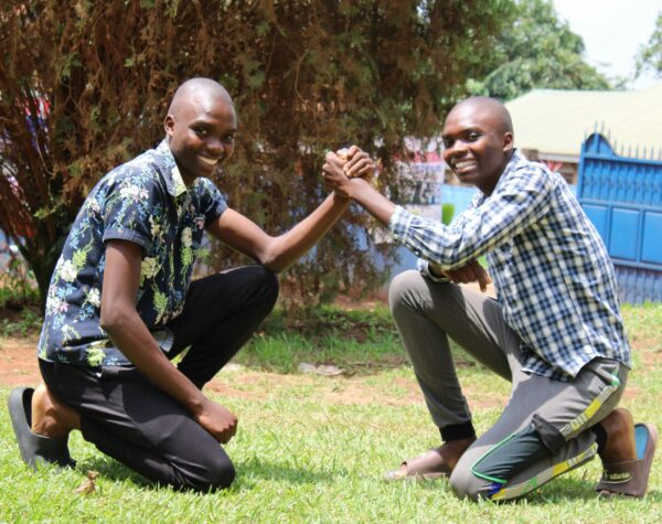 Twin brothers kneeling and clasping hands
