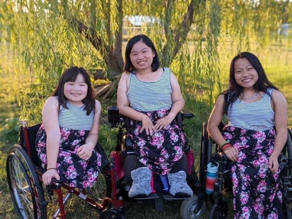 Three sisters sitting in wheelchairs dressed alike