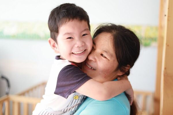 Chinese boy hugging his nanny's neck