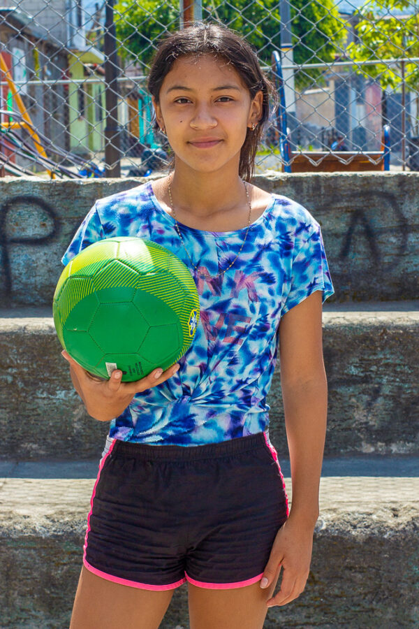 Girl in Guatemala holding a green soccer ball