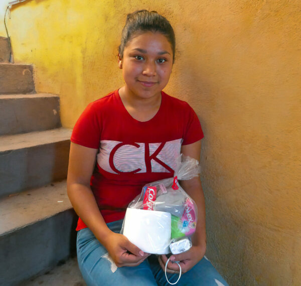 Girl in red shirt sitting on steps holding a plastic bag