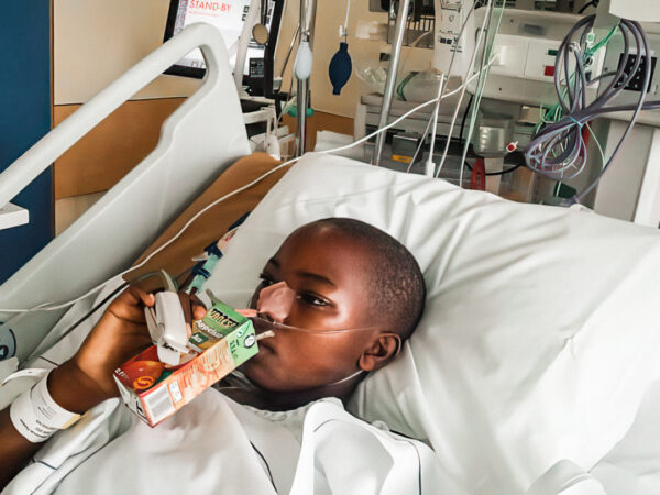 Girl drinking juice box in hospital bed