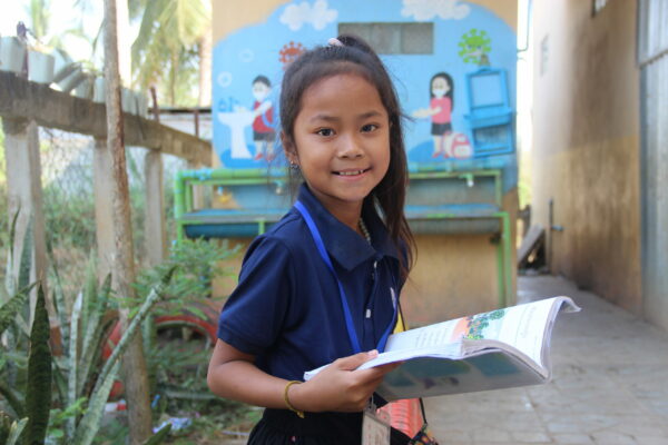 Girl in Cambodian school uniform reading a book