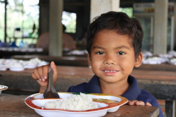 Boy eating hot lunch at a Cambodian school