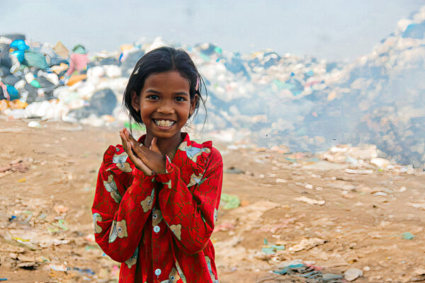 Girl in red shirt in front of a landfill