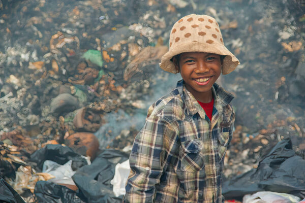 Girl in brown polka dot hat and plaid shirt at a landfill