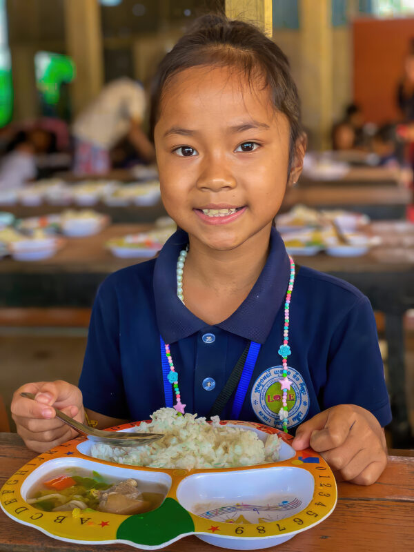 Girl in Cambodian school uniform eating lunch
