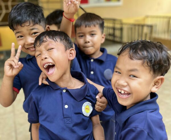 Four boys laughing in Cambodian school uniforms