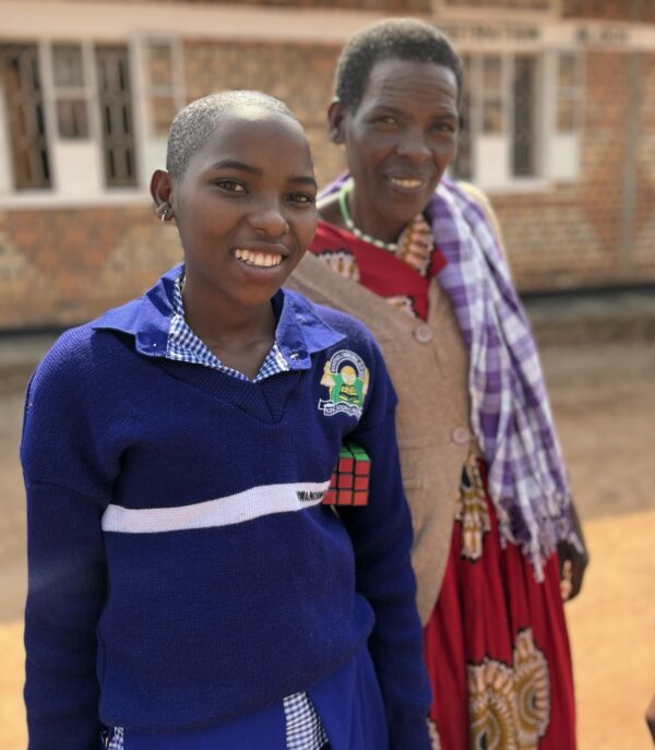 Ugandan schoolgirl holding a Rubik's cube standing with her mother