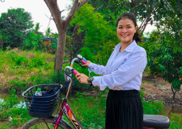Teen girl going to school with a bicycle in Cambodia
