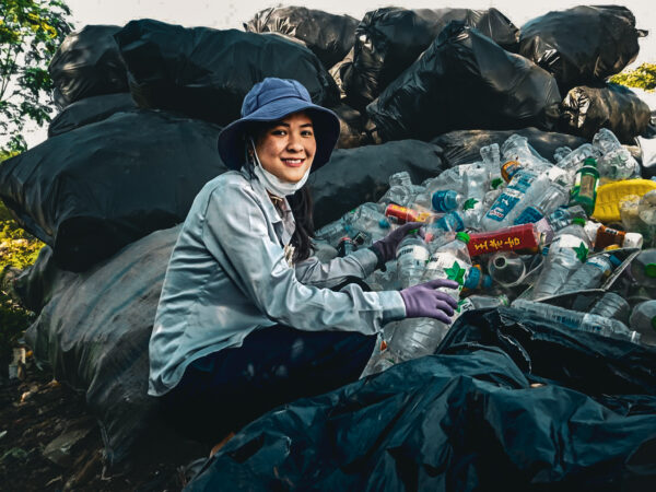 Young woman in a blue hat sorting recyclables at a landfill