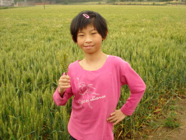 Girl in a pink shirt standing in a green field