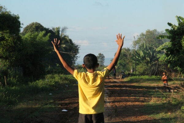 Boy in a yellow shirt holding hands in the air