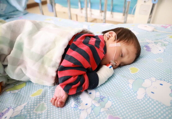 Toddler girl in red and blue stripes sleeping in hospital