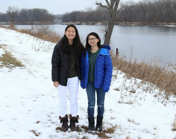 Two girls standing by a lake in the snow