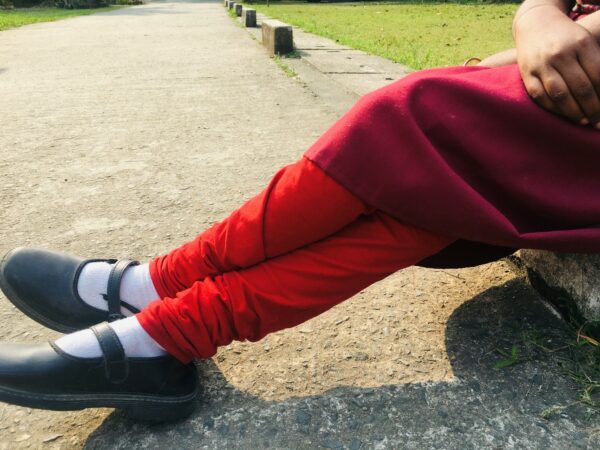 Girl's crossed legs in red pants and black shoes