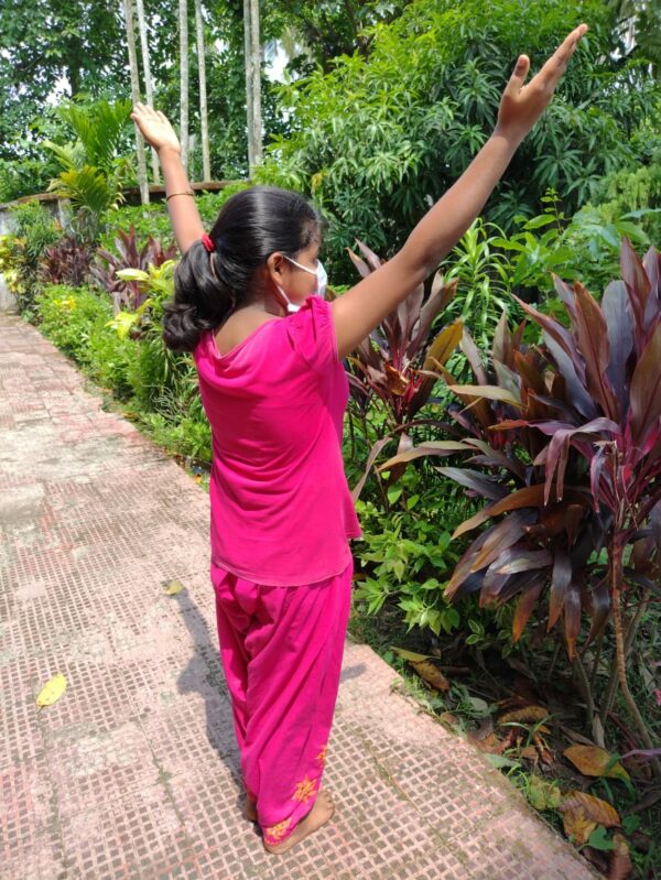 Girl with two arms in the air in a garden