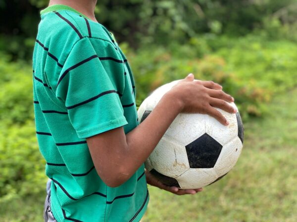 Boy in green striped shirt holding a soccer ball