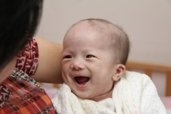 Baby looking at woman and laughing with mouth wide open