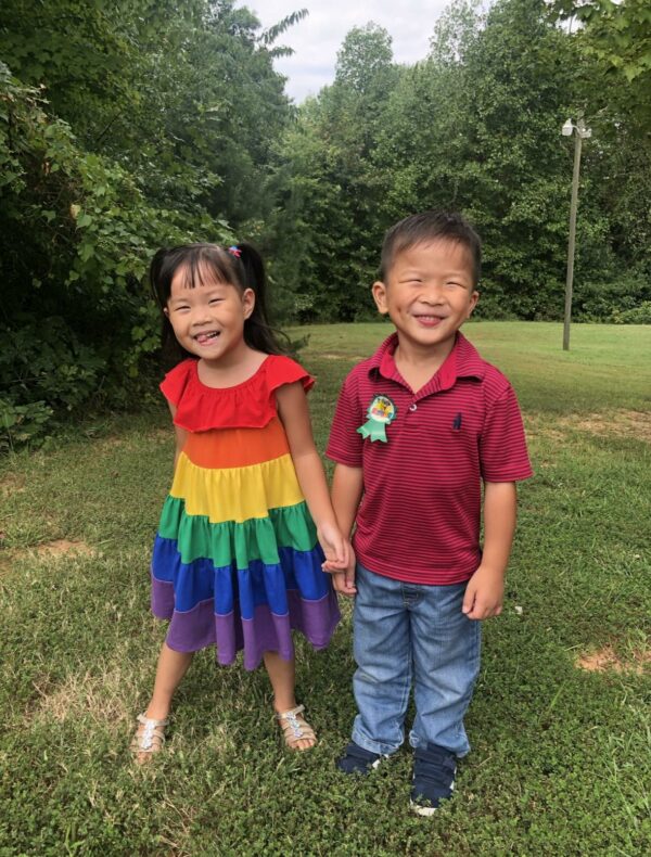 Sister and brother holding hands and smiling outside