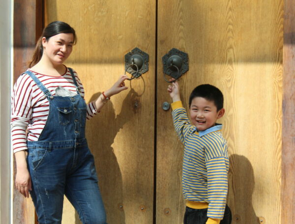Mother and son stand in front of wooden door