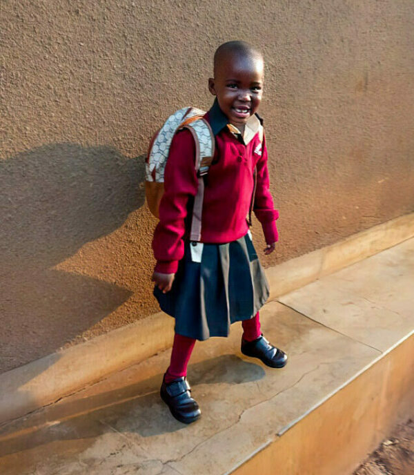 Uganda schoolgirl wearing a red sweater and grey skirt