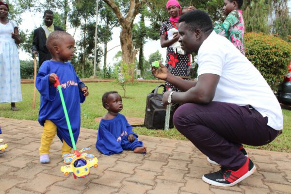 Man showing toys to two children during a Uganda Hernia Mission trip