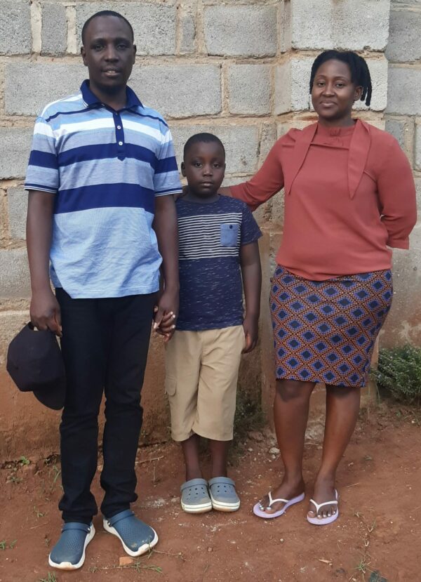 Mom and dad with young son in front of a cement block wall