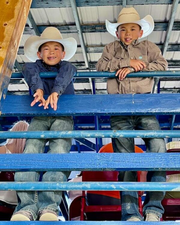 Twin boys in cowboy hats at the rodeo