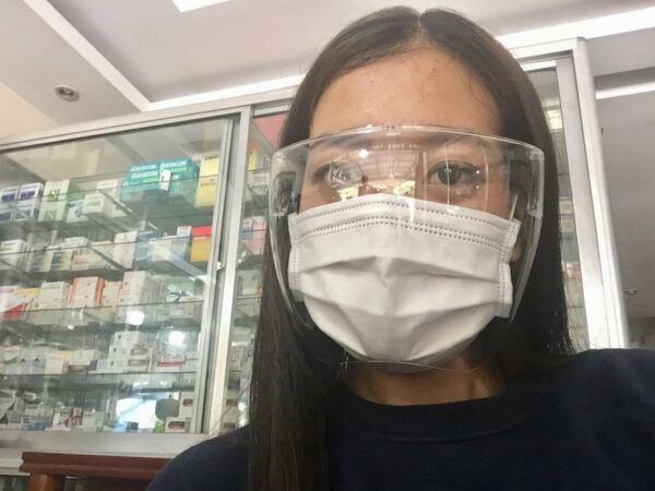 Young woman wears goggles and a mask in a pharmacy