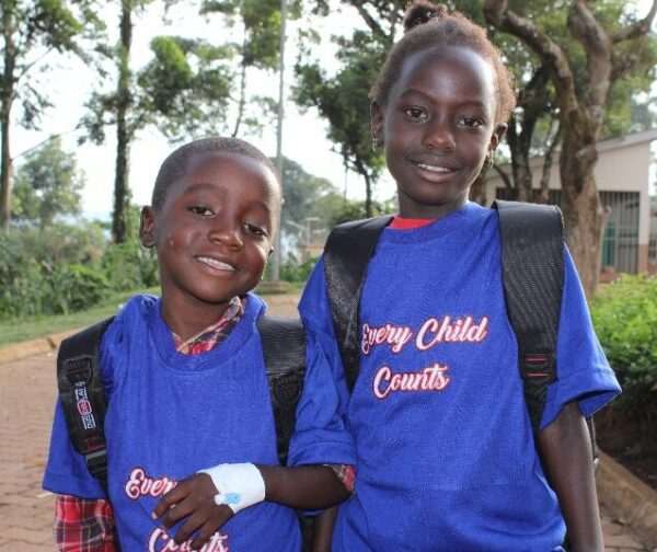 Two sisters in blue shirts before a Uganda Hernia Mission