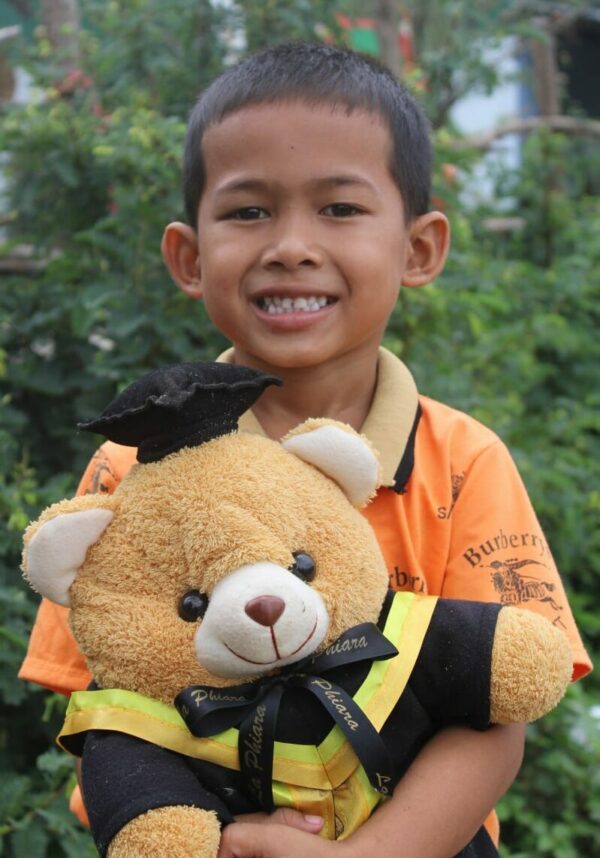 Boy in orange shirt holding a big teddy bear