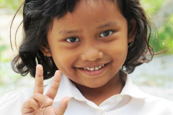 Little girl in a white shirt giving the peace sign