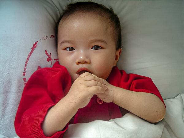 Girl in hospital bed in China wearing a red top