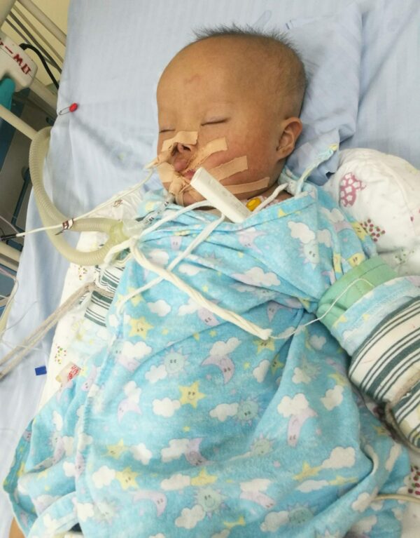 Baby boy lying in hospital bed with tubes